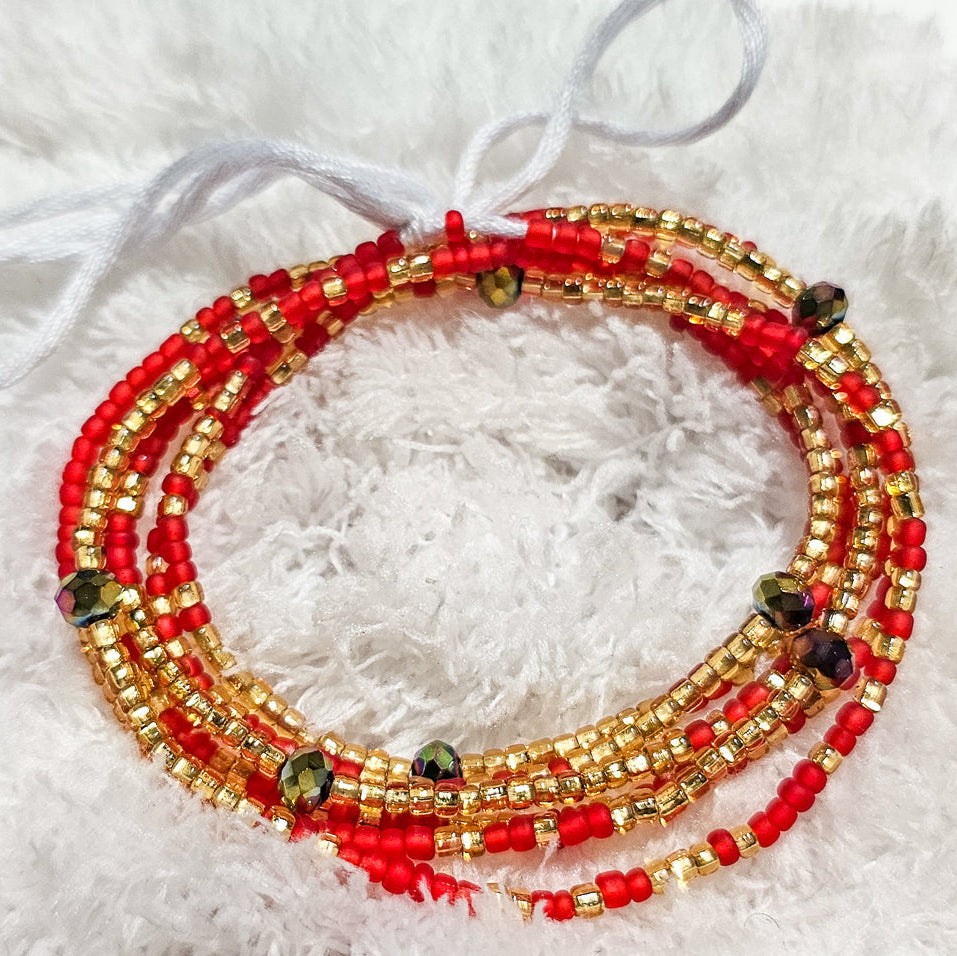 Red and gold beaded bracelet on a white fluffy background