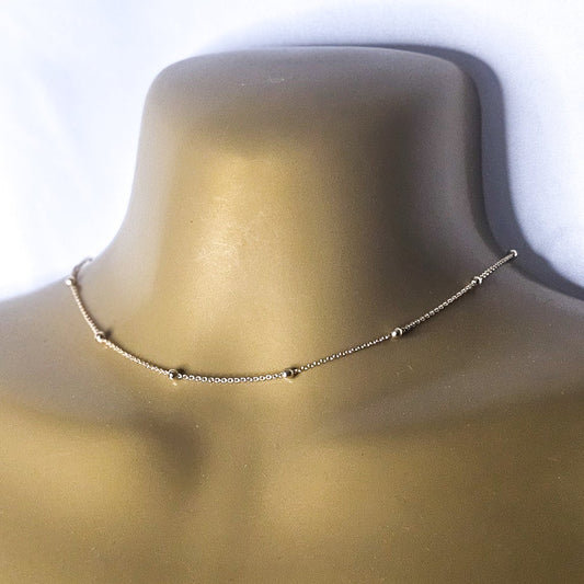 Gold necklace on a mannequin with a white background
