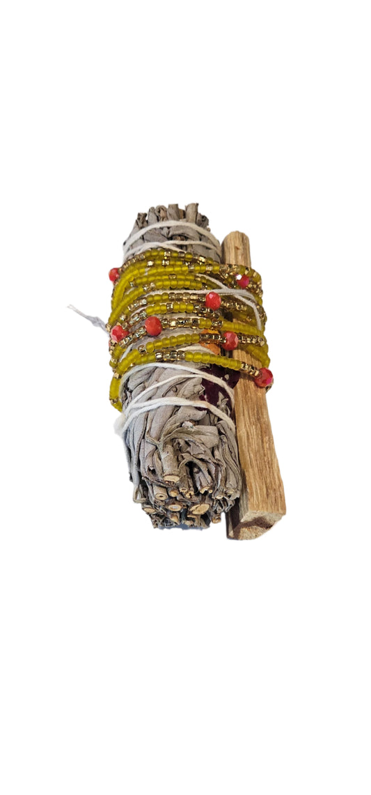 Bundled sage with red beads on a white background